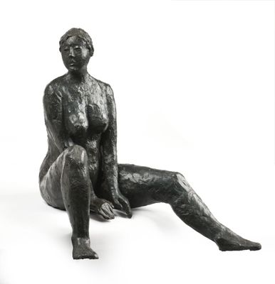 une statue représentant une femme assise sur une surface blanche