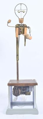 statue d'un homme assis sur une table en bois, à côté d'une horloge