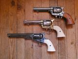trois revolvers sont alignés les uns à côté des autres sur un plancher en bois