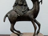 a statue of a man riding a camel on a wooden block