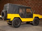 a yellow jeep parked in front of a brick wall