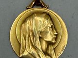 l'image d'une médaille d'or sur laquelle figure le visage d'une femme