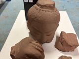 a clay sculpture of a head on a table next to rocks