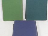 three books sitting on top of a white surface next to each other