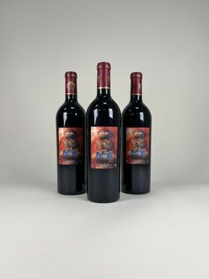three bottles of red wine sitting next to each other on a table
