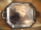 a silver tray with a handle on a gold cloth
