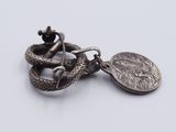 a silver coin with a snake on it and a coin on a chain