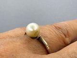 someone is holding a ring with a pearl in it on their finger