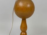 une boule en bois posée sur un socle en bois et attachée à une cordelette