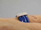 someone is holding a blue and white ring with diamonds on it