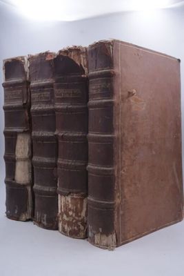 trois vieux livres sont empilés sur une surface blanche