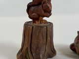 two figurines of squirrels sitting on top of a tree stump