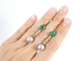 someone is holding a pair of rings with pearls and emeralds