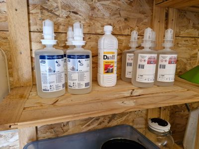 plusieurs bouteilles de liquide posées sur une étagère à côté d'une poubelle