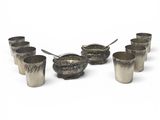several silver cups with spoons and spoon rest on a white surface