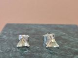 pair of silver earrings with a yellow diamond on a marble block