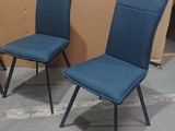two blue chairs sitting next to each other in a room