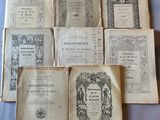 Plusieurs vieux livres sont posés sur une table recouverte d'un tissu bleu.