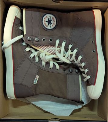 des chaussures Converse dans une boîte posée sur une table recouverte d'une nappe blanche