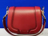 un gros plan d'un sac à main rouge posé sur une table blanche