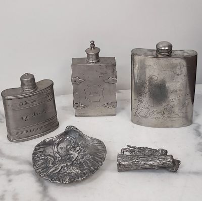 trois flacons en argent et une cuillère en argent posés sur une table en marbre