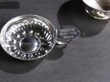 a silver cup and saucer sitting on a table