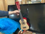 a person holding a guitar in front of a television