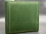 a green leather book with gold trims on a grey background