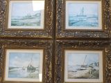 quatre tableaux encadrés représentant des bateaux sur une plage et un bateau dans l'eau
