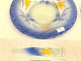 a blue plate with yellow flowers on it next to two spoons and a glass plate