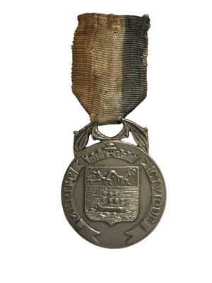une vieille médaille en argent sur fond blanc, ornée d'un ruban noir et or