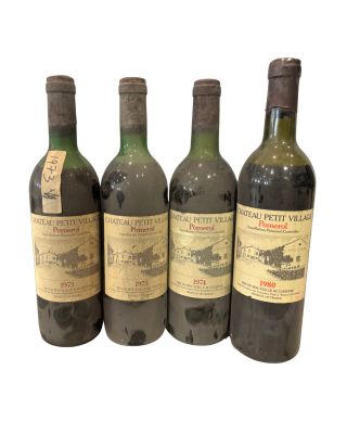 quatre bouteilles de vin sont alignées sur une surface blanche