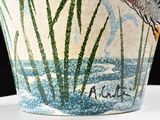 a vase with a bird on it sitting on a table