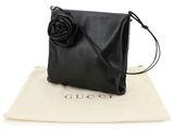 a black leather bag with a rose on the front