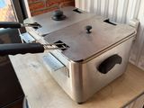 a silver fryer sitting on top of a table next to a window