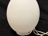 a white lamp with a cord attached to it on a black background