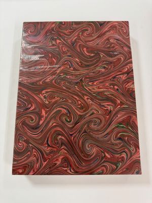 a red and black marbled notebook sitting on top of a white table