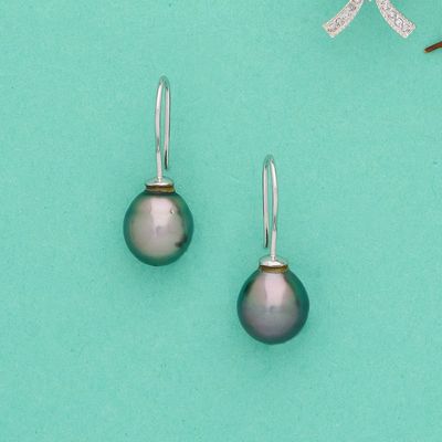 une paire de boucles d'oreilles en argent et perles noires sur fond turquoise