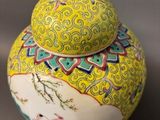 a yellow and blue vase with a lid on a table