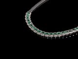 un gros plan d'un collier de diamants et d'émeraudes sur fond noir
