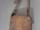 sac à main en cuir beige muni d'une bandoulière, posé sur une surface blanche, sur fond blanc