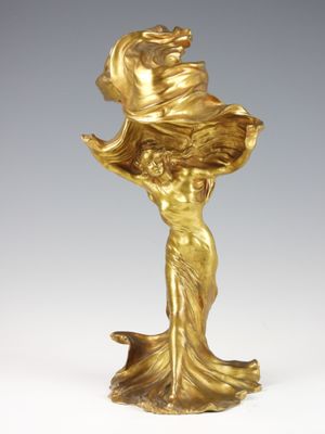 une statue en or représentant une femme tenant une fleur à la main
