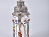 a beer mug with a statue on top of it