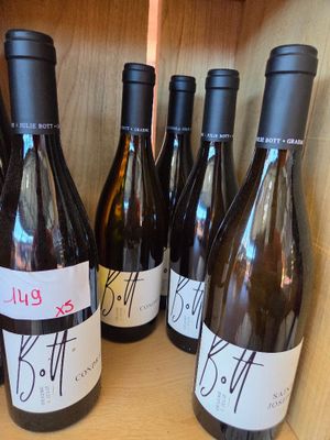 several bottles of wine are lined up on a wooden shelf