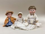 trois poupées en porcelaine représentant des enfants assis sur une couverture