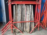 un tas de bois posé par terre à côté d'un échafaudage rouge