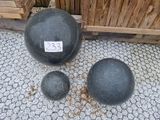 two large black balls sitting next to each other on the ground