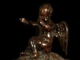 bronze statue of an angel sitting on top of a wooden base