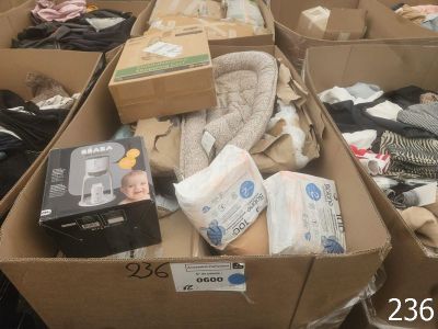 Plusieurs cartons de vêtements pour bébés et de couches sont empilés les uns sur les autres