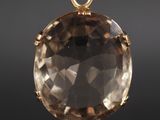 un gros plan d'un pendentif plaqué or orné d'un gros quartz fumé facetté